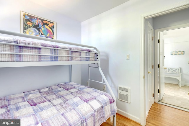 bedroom featuring heating unit and wood-type flooring