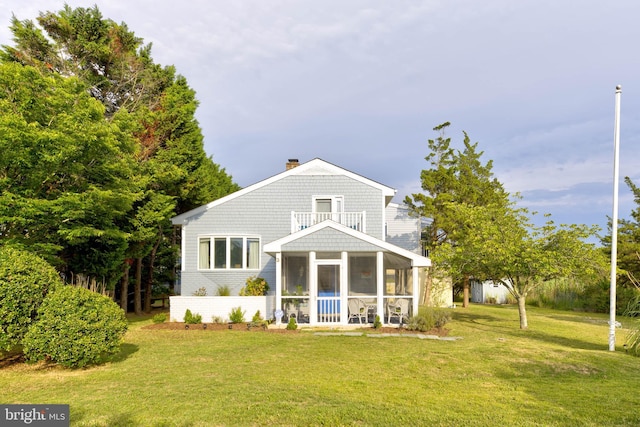 back of property with a balcony, a yard, and a sunroom