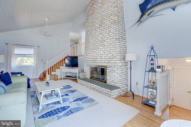 living room with a fireplace, light hardwood / wood-style flooring, ceiling fan, and vaulted ceiling