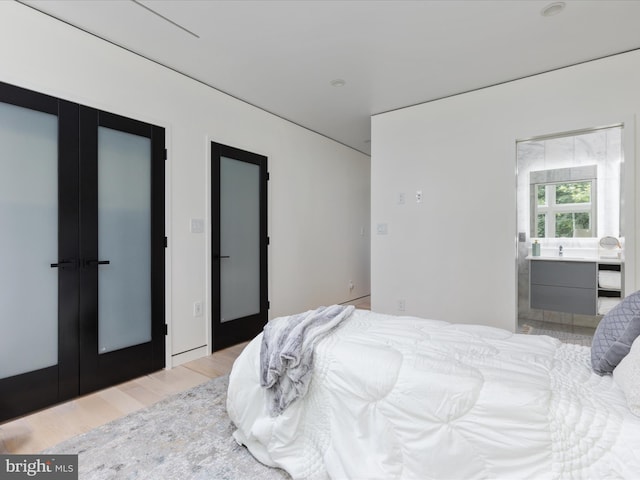 bedroom featuring french doors and light hardwood / wood-style flooring