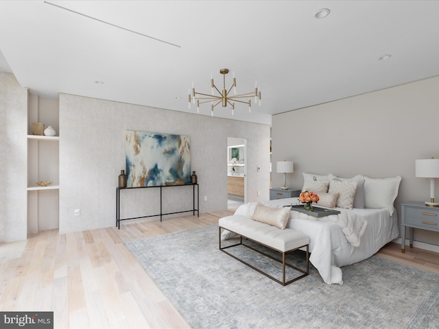 bedroom featuring an inviting chandelier, connected bathroom, and hardwood / wood-style flooring