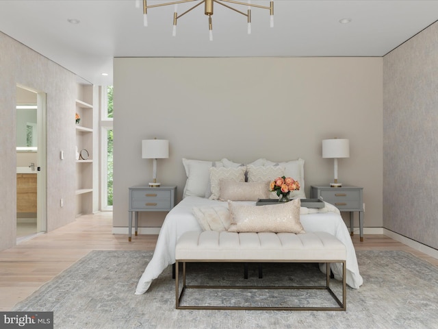 bedroom with ensuite bath, a notable chandelier, and light hardwood / wood-style floors