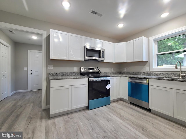 kitchen featuring sink, white cabinets, stainless steel appliances, and light hardwood / wood-style floors