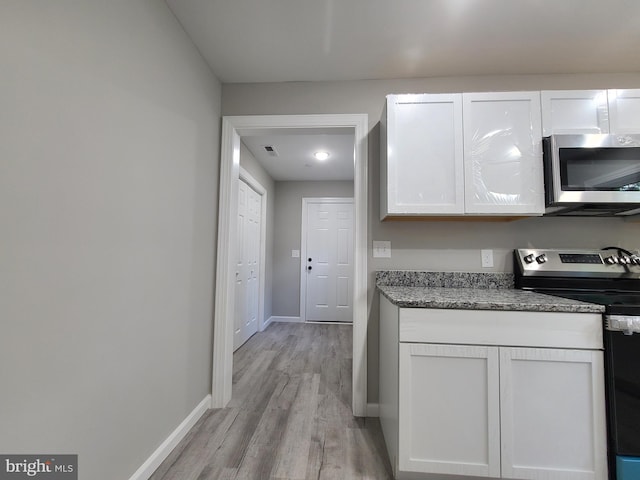 kitchen featuring white cabinets, range with electric cooktop, stone counters, and light hardwood / wood-style flooring