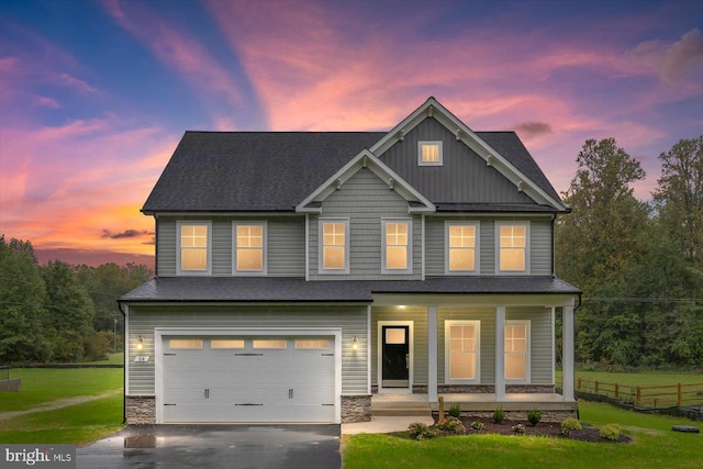 craftsman-style home with covered porch, a garage, and a lawn