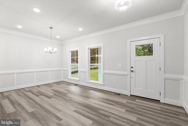 foyer with a healthy amount of sunlight, crown molding, and light hardwood / wood-style floors