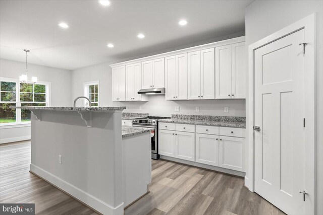 kitchen with light hardwood / wood-style flooring, stainless steel gas stove, white cabinets, and an island with sink