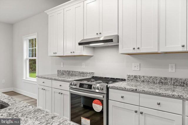 kitchen featuring stainless steel range, light stone countertops, white cabinetry, and light hardwood / wood-style flooring