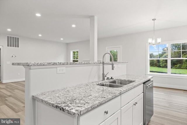 kitchen featuring white cabinetry, a center island with sink, decorative light fixtures, stainless steel dishwasher, and sink