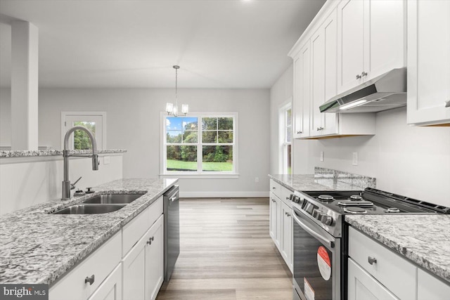 kitchen with sink, hanging light fixtures, light stone countertops, appliances with stainless steel finishes, and white cabinets