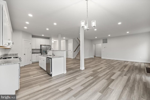 kitchen with light hardwood / wood-style floors, a center island with sink, sink, appliances with stainless steel finishes, and white cabinets