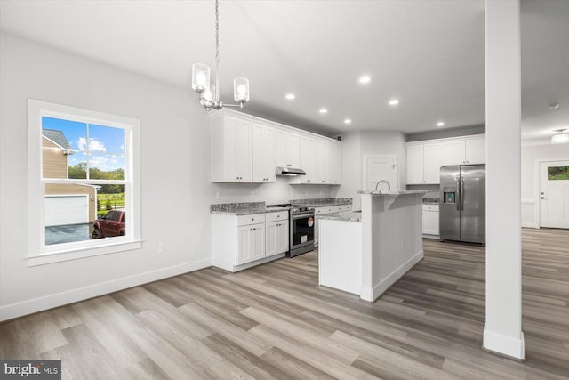 kitchen featuring white cabinetry, stainless steel appliances, decorative light fixtures, a kitchen island with sink, and light stone countertops