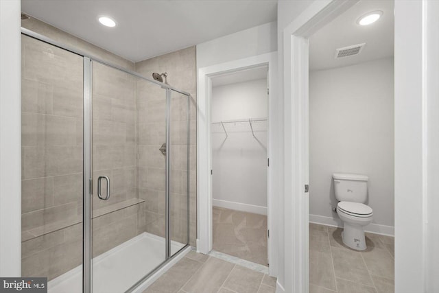 bathroom featuring toilet, tile patterned flooring, and an enclosed shower