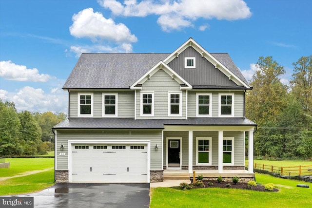 craftsman-style home featuring a front lawn, covered porch, and a garage