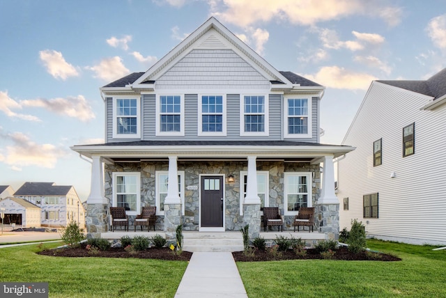 craftsman-style home with a porch, a front yard, and stone siding