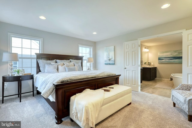 bedroom with ensuite bathroom, recessed lighting, baseboards, and light colored carpet