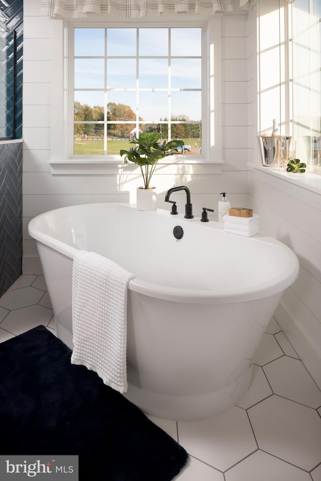 bathroom with tile patterned flooring, tile walls, and a wealth of natural light