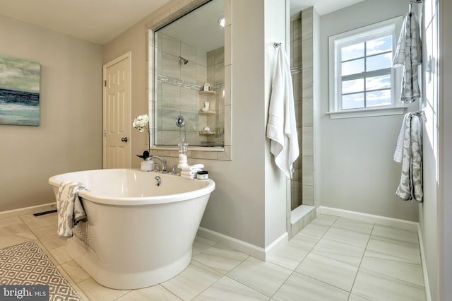 full bath featuring tiled shower, a freestanding tub, and baseboards