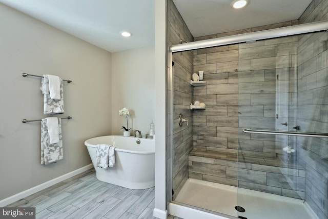 bathroom featuring recessed lighting, wood tiled floor, a shower stall, a freestanding tub, and baseboards