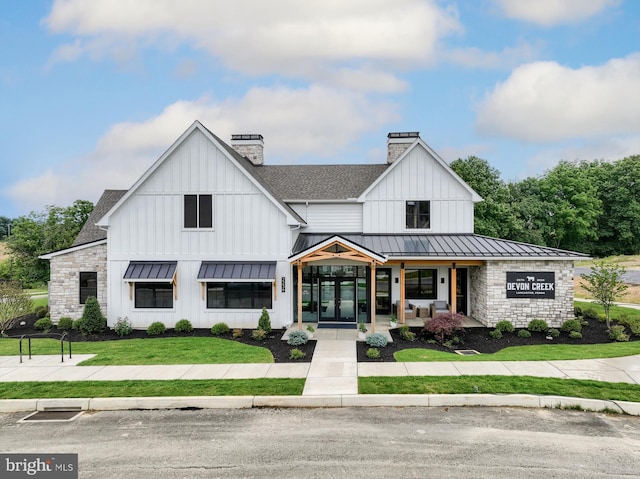 modern farmhouse style home featuring a chimney, roof with shingles, a standing seam roof, french doors, and a front lawn