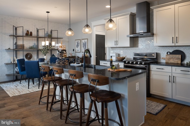 kitchen with a breakfast bar area, wall chimney range hood, backsplash, dark countertops, and dark wood finished floors