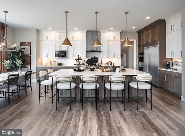 kitchen with appliances with stainless steel finishes, decorative light fixtures, a large island, and a breakfast bar area