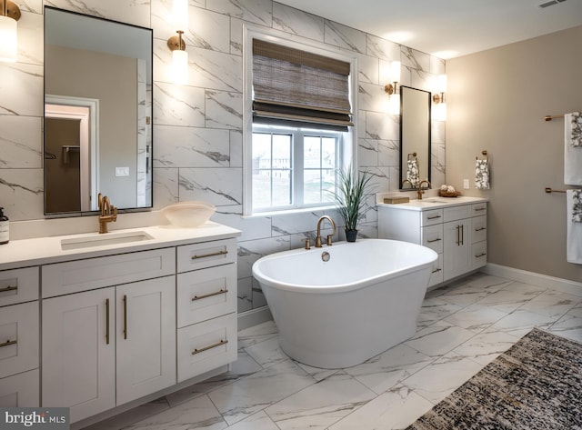 bathroom featuring visible vents, a freestanding bath, a sink, two vanities, and marble finish floor
