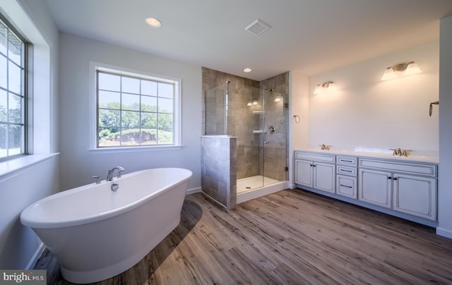 full bath with visible vents, a sink, a soaking tub, wood finished floors, and a stall shower
