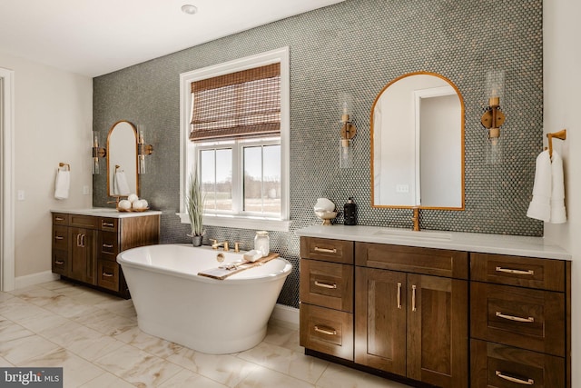 bathroom featuring baseboards, a freestanding tub, marble finish floor, and vanity