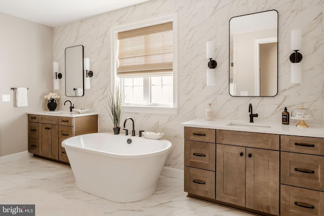full bath featuring two vanities, marble finish floor, and a sink