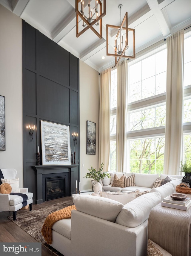 living room with hardwood / wood-style floors, coffered ceiling, beamed ceiling, a large fireplace, and a chandelier