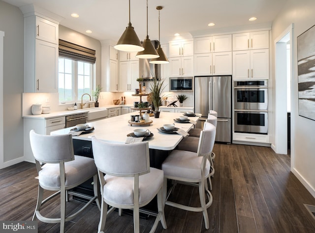 kitchen featuring pendant lighting, a center island, appliances with stainless steel finishes, dark hardwood / wood-style flooring, and white cabinetry