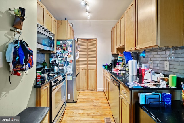 kitchen with appliances with stainless steel finishes, light wood-type flooring, track lighting, backsplash, and sink