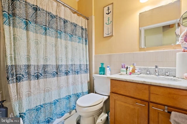 bathroom featuring vanity, tile walls, and toilet