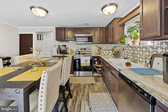 kitchen with appliances with stainless steel finishes, hardwood / wood-style flooring, sink, and backsplash