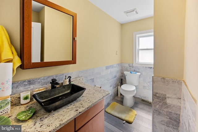 bathroom with tile walls, toilet, and vanity