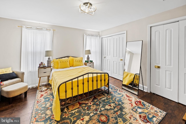 bedroom featuring hardwood / wood-style flooring, two closets, and multiple windows