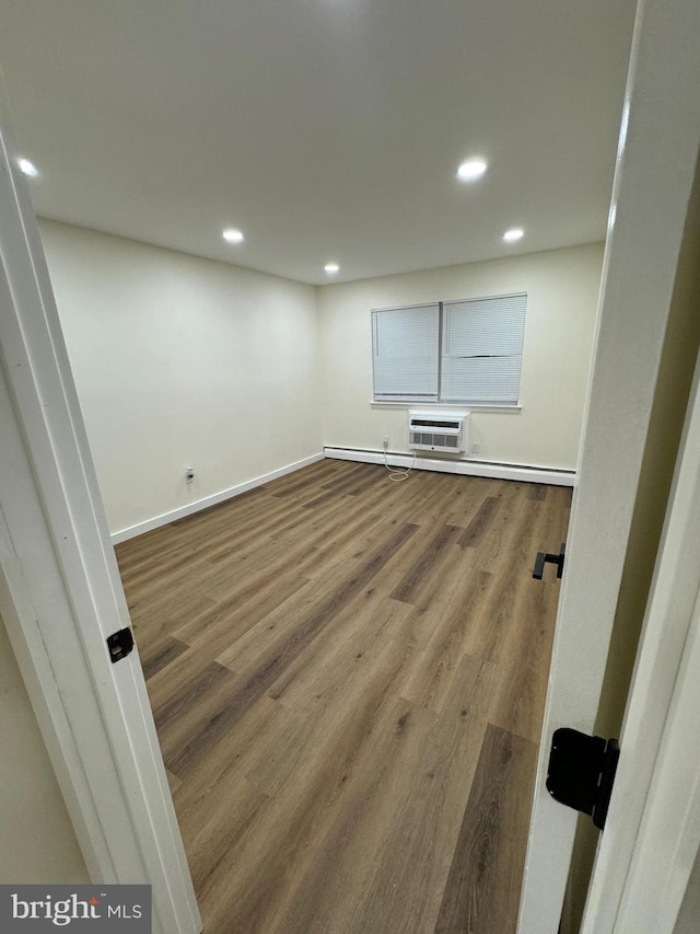 basement featuring a wall mounted air conditioner and hardwood / wood-style flooring