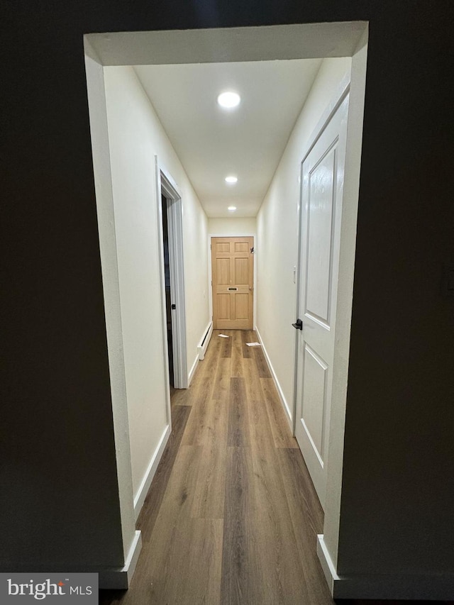 hallway with wood-type flooring and a baseboard radiator