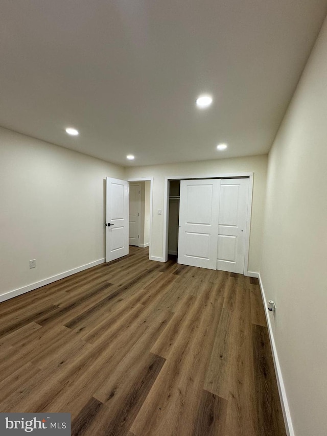 unfurnished bedroom featuring a closet and dark wood-type flooring