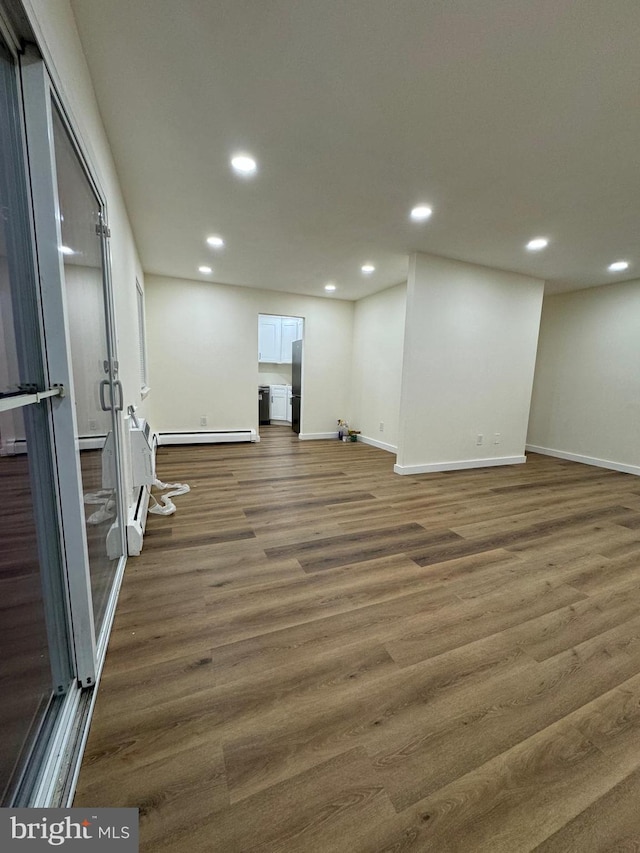 basement featuring dark hardwood / wood-style floors, stainless steel refrigerator, and baseboard heating