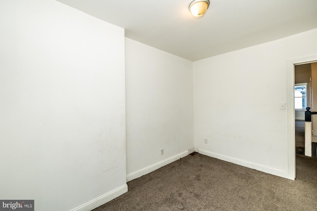 spare room with dark carpet