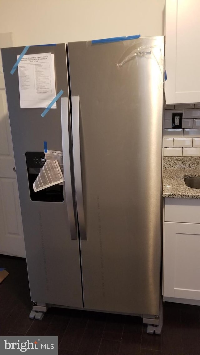 interior details with light stone counters, stainless steel fridge with ice dispenser, tasteful backsplash, and white cabinets