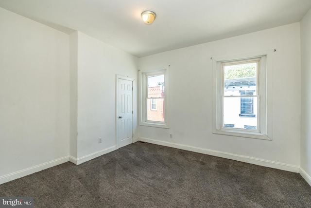 unfurnished room featuring dark carpet