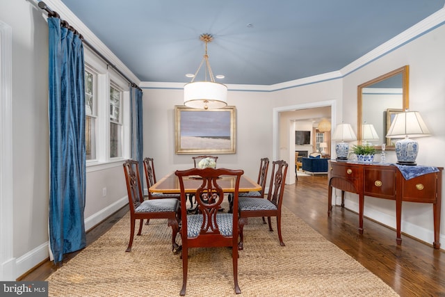 dining space with baseboards, wood finished floors, and ornamental molding