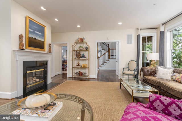 living area with recessed lighting, a fireplace, wood finished floors, visible vents, and stairway