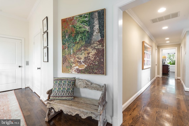 hallway featuring baseboards, crown molding, visible vents, and wood finished floors