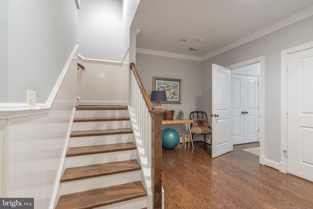 stairs featuring crown molding and wood finished floors