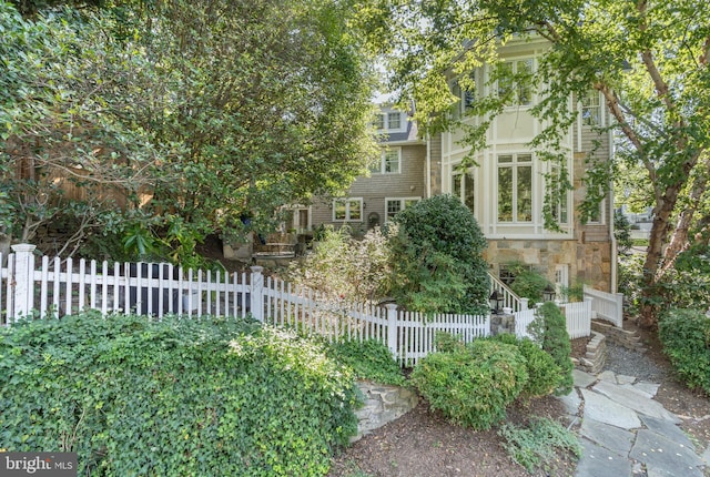 view of front of home with stone siding and a fenced front yard