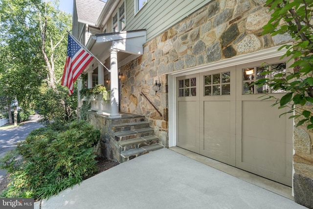 property entrance with a garage and stone siding